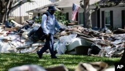 Lonzell Rector, un cartero de Houston hace su ronda diaria en medio de los escombros de casas afectadas por la inundación causada por el huracán Harvey. Sept. 7, 2017. 
