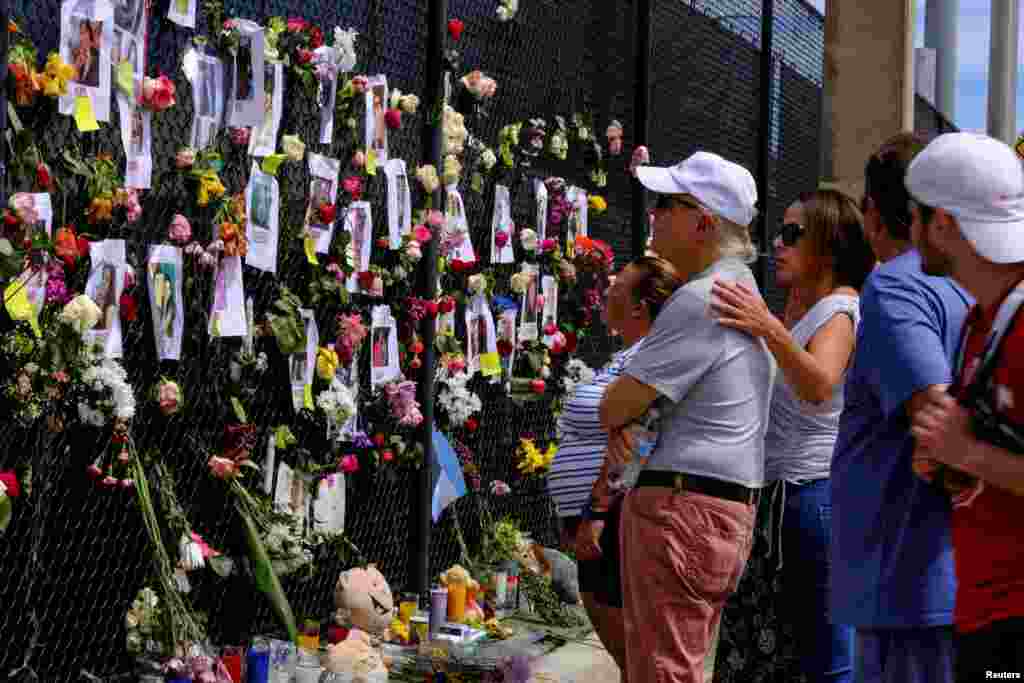 La gente llora en el sitio conmemorativo creado por los vecinos frente al edificio parcialmente derrumbado donde el personal de rescate continúa la búsqueda de víctimas.