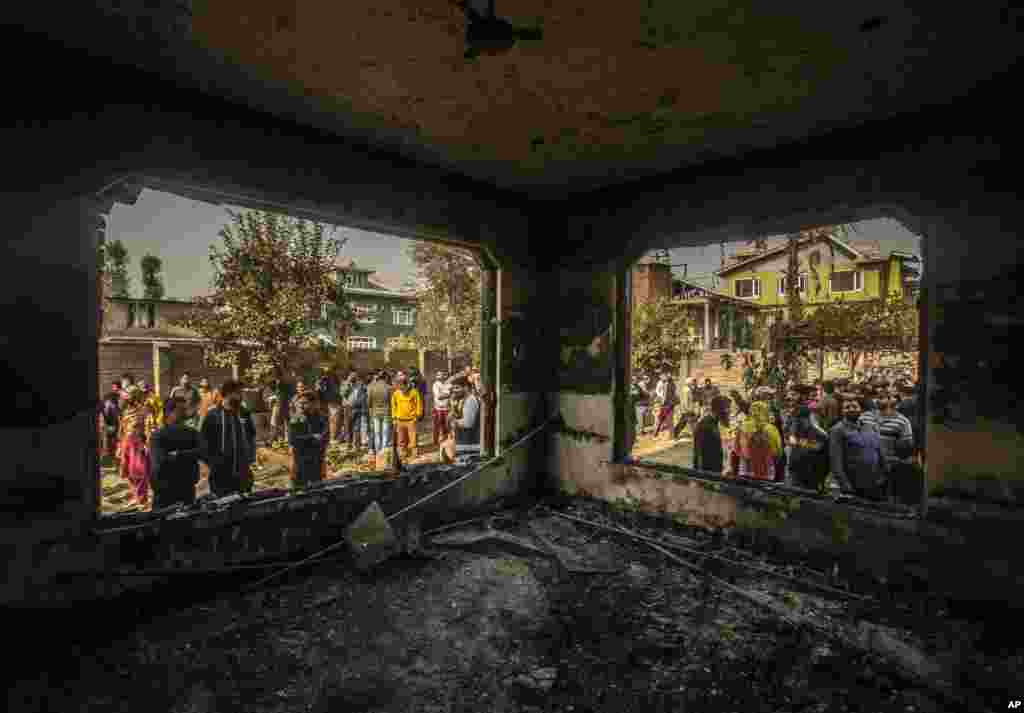 Kashmiris assemble near a house damaged after a gunbattle in Srinagar, Indian controlled Kashmir.