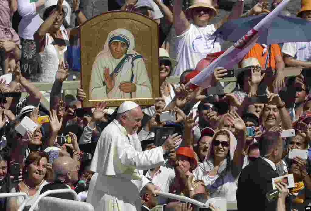 Paus Fransiskus melewati potret Bunda Teresa saat kendaraannya melalui massa usai upacara kanonisasi di Lapangan Santo Petrus, Vatikan (4/9). (AP/Alessandra Tarantino)