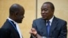 Kenya's President Uhuru Kenyatta (R) speaks to a member of his defense team as he appears before the International Criminal Court at The Hague, Oct. 8, 2014.