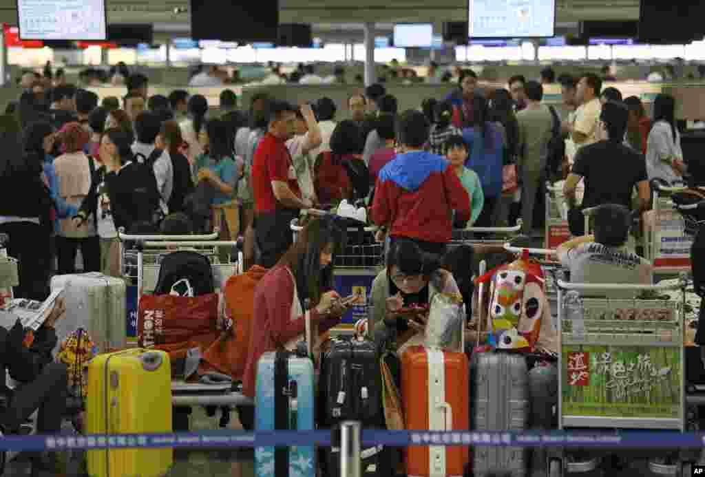 Para penumpang yang terpengaruh Topan Usagi menanti di bandar udara internasional Hong Kong (23/9). Lebih dari 370 penerbangan dibatalkan akibat topan ini. (AP/Vincent Yu)