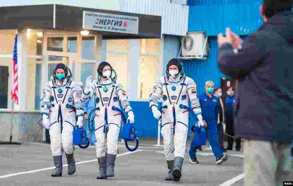 Expedition 64 NASA astronaut Kate Rubins, left, Russian cosmonauts Sergey Ryzhikov, center, and Sergey Kud-Sverchkov, right, depart Building 254 to head to their launch onboard the Soyuz MS-17 spacecraft, at the Baikonur Cosmodrome in Kazakhstan.