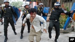 Seorang buruh Kamboja yang terluka lari dari kejaran polisi anti huru-hara Kamboja dalam protes di Phnom Penh, Selasa (12/11). 