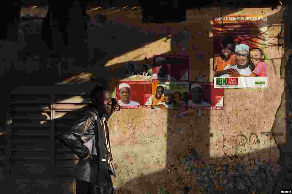 Issa Djire, a supporter of presidential candidate Dramane Dembele, stands next to posters of Dembele outside his house in Bamako, Mali, July 22, 2013.