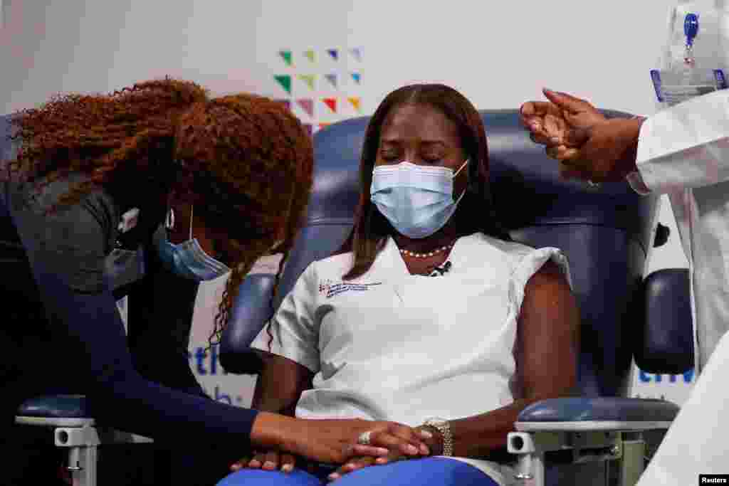 Mavis Knox, L, prays just before nurse Sandra Lindsay, R, receives the second dose of a Pfizer COVID-19 vaccine at Long Island Jewish Medical Center in the Queens borough of New York City.