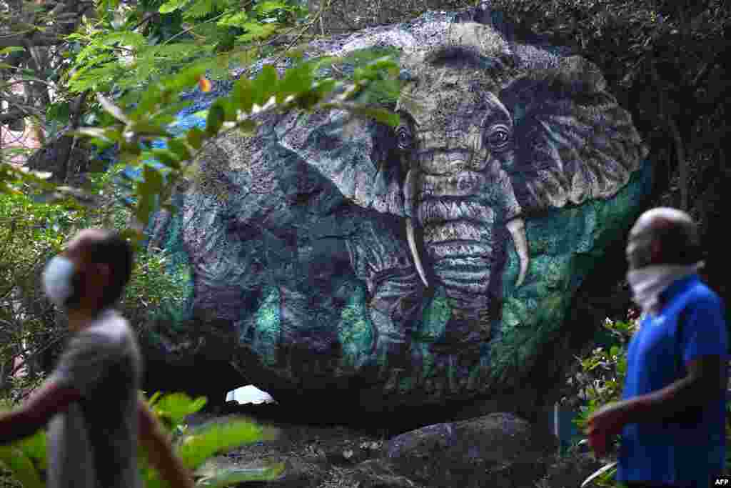 Morning walkers pass a mural of an elephant created as part of a city beautification initiative taken by local civic body at a public garden in Mumbai, India.