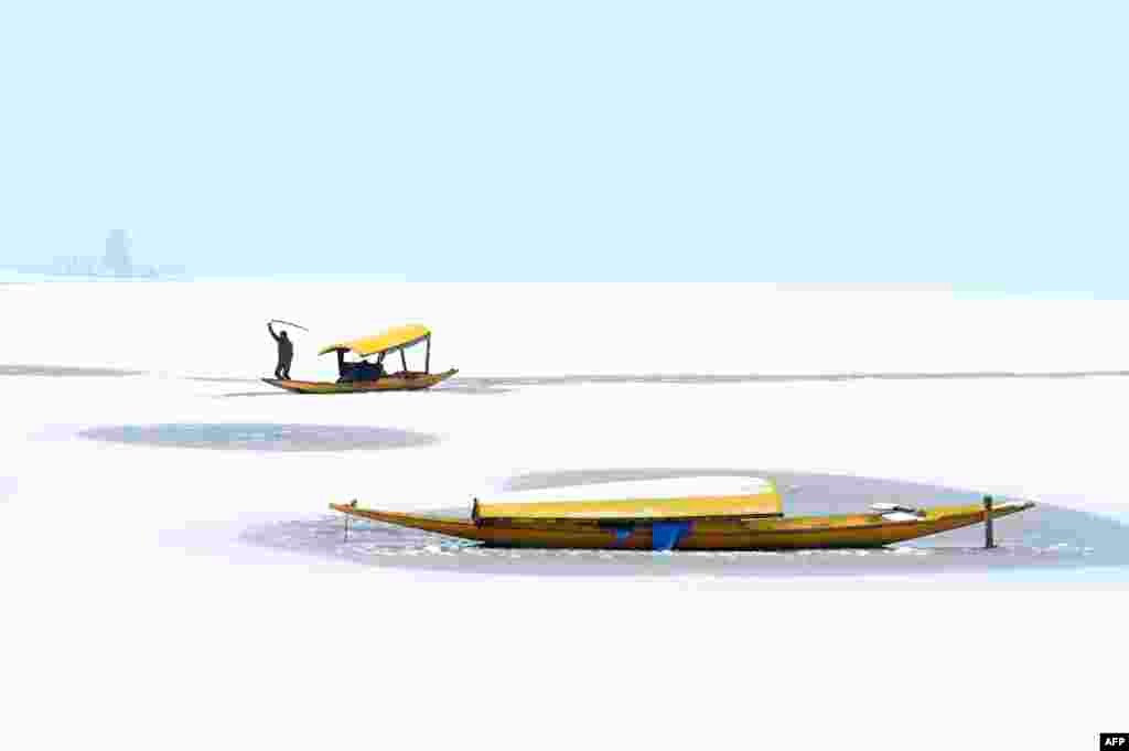 A boatman steers his boat at the partially frozen Dal Lake after a snowfall in Srinagar, India.