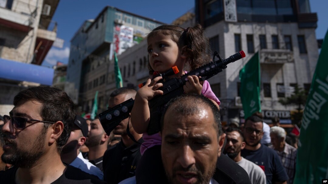 Palestinska devojčica sa plastičnom puškom na očevima ramenima tokom protesta u Ramali na Zapadnoj obali (Foto: AP/Nasser Nasser)