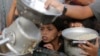 Un niño palestino observa mientras le sirven una ración de comida antes de la fiesta del Eid al-Adha, en Jan Yunis, Gaza, el 15 de junio de 2024. 