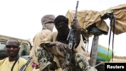 FILE - Militiaman from the Ansar Dine Islamic group sit on a vehicle in Gao in northeastern Mali, June 18, 2012. 