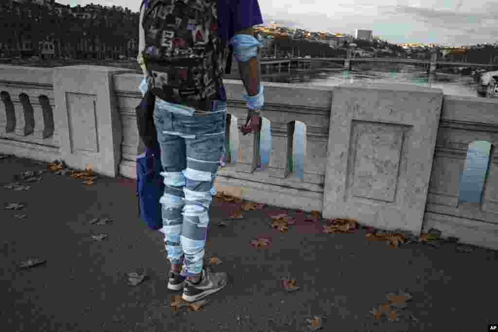 A man wearing face masks on his legs stands on a bridge in the center of Lyon, central France.