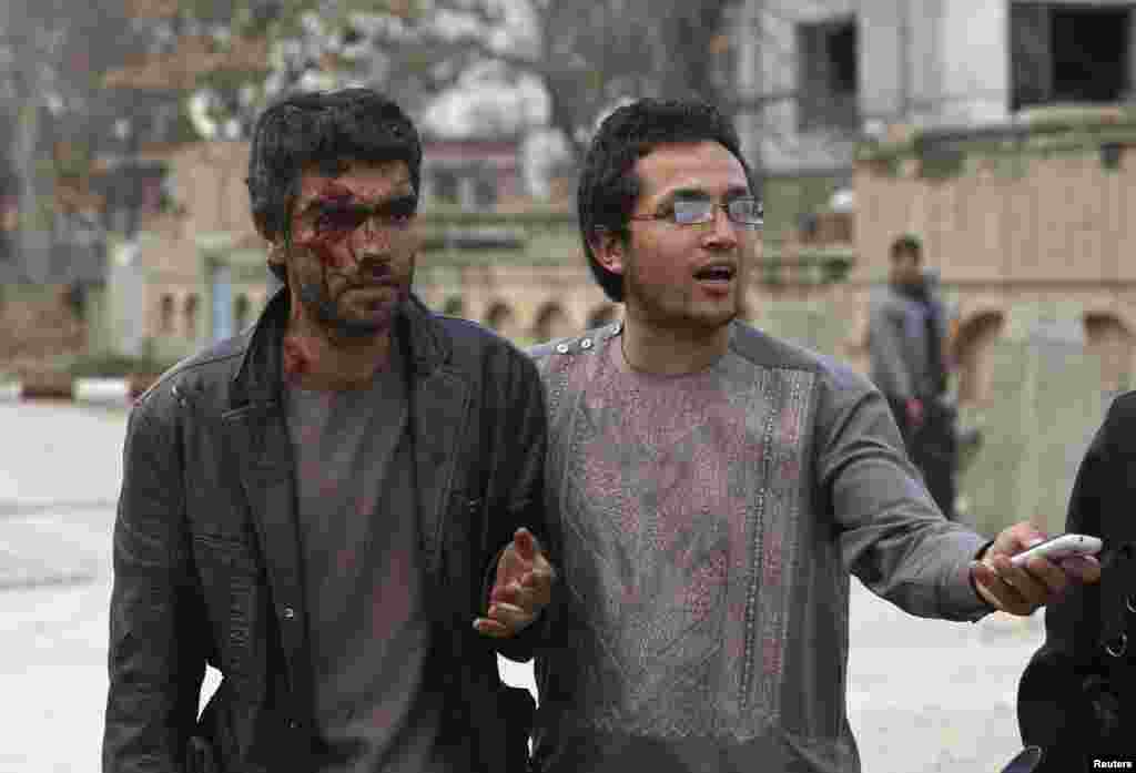An Afghan man helps an injured man at the site of an attack in Kabul, March 28, 2014.