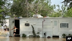 Una mujer sale de una casa móvil en un área no incorporada en el este del condado de Harris, cerca de Houston, el sábado 4 de mayo de 2024 por la tarde. Intensas lluvias han provocado fuertes inundaciones en la región.