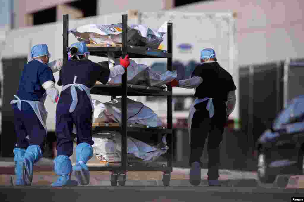 El Paso County Medical Examiner's Office staff roll bodies that are in bags labeled "Covid" from refrigerated trailers into the morgue office amid the COVID-19 outbreak, in El Paso, Texas, Nov. 23, 2020.