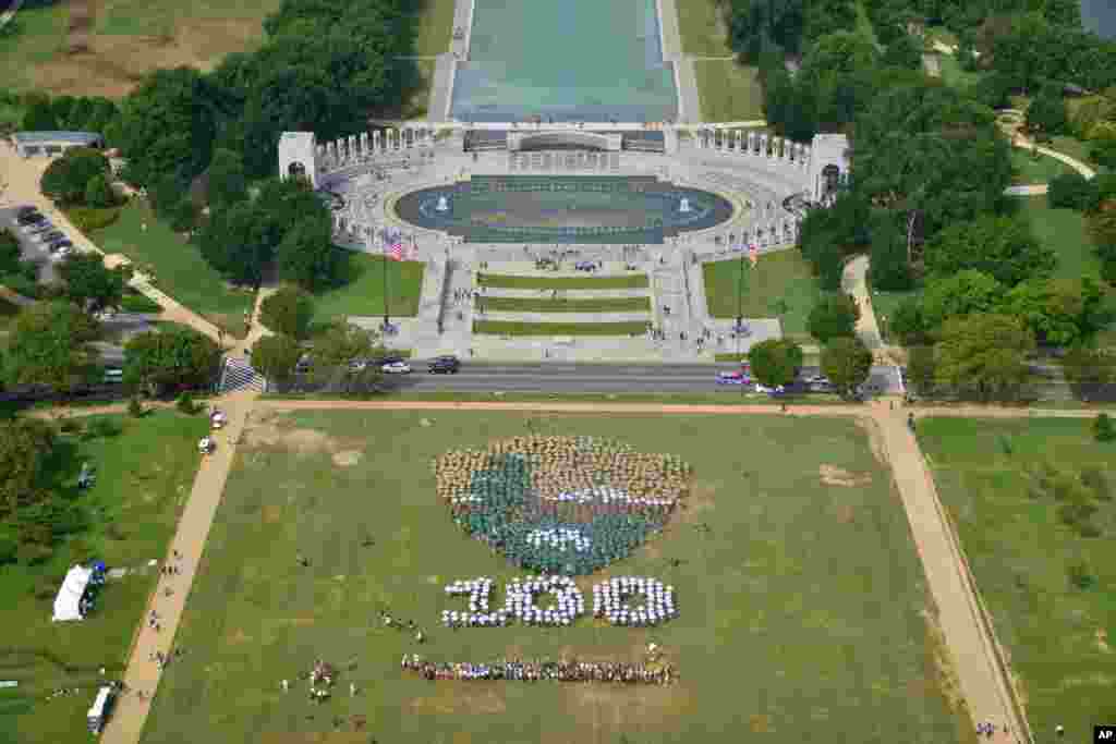 People create a giant, living National Park Service arrowhead, using brown, green and white umbrellas, on the National Mall in Washington, D.C., to celebrate the 100th anniversary of the agency.