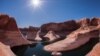 A houseboat sits in the green water and high orange cliffs of Lake Powell. The dramatic curves of Reflection Canyon show the path the river once took before Lake Powell. (Photo: NPS / Gary Ladd)