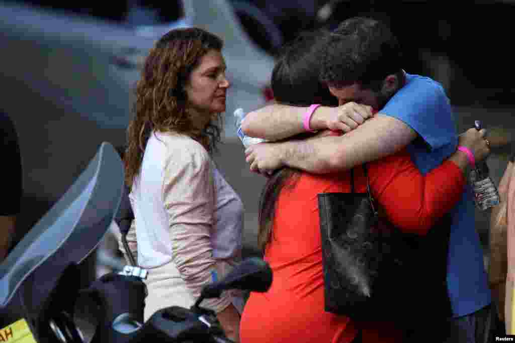 Los familiares de los desaparecidos reportados se abrazan en la entrada de un hotel después de visitar el sitio del edificio residencial parcialmente derrumbado.