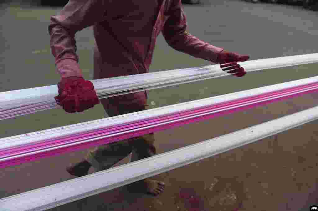 A man coats strings for flying kites with colored glass powder ahead of 'Uttarayan' or Kite festival, in Ahmedabad, India.