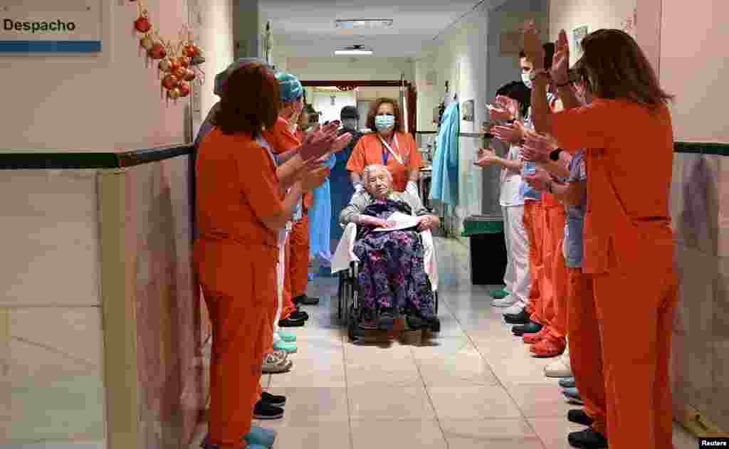 Health workers salute Elena, 104, as she leaves the Gregorio Maranon hospital, after being treated for the COVID-19 in Madrid, Spain. (Hospital Gregorio Maranon/Handout)