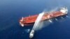 An Iranian navy boat sprays water to extinguish a fire on an oil tanker in the sea of Oman, June 13, 2019.