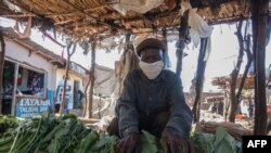 FILE - A vendor displays vegetables at his stand, as he wears a face mask to protect against the coronavirus, at an agricultural commodity market in Lilongwe, Malawi, May 4, 2020.