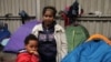 FILE - Tsega, 38, a migrant who fled Eritrea six years ago, poses with her son Naher, 5, in front of their tent at a migrant shelter in Calais, northern France, October 2014.