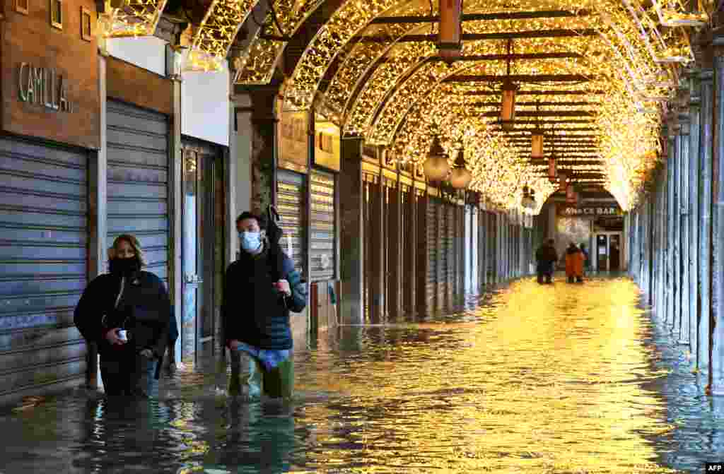 People walk across an arcade by a flooded St. Mark's Square in Venice.
