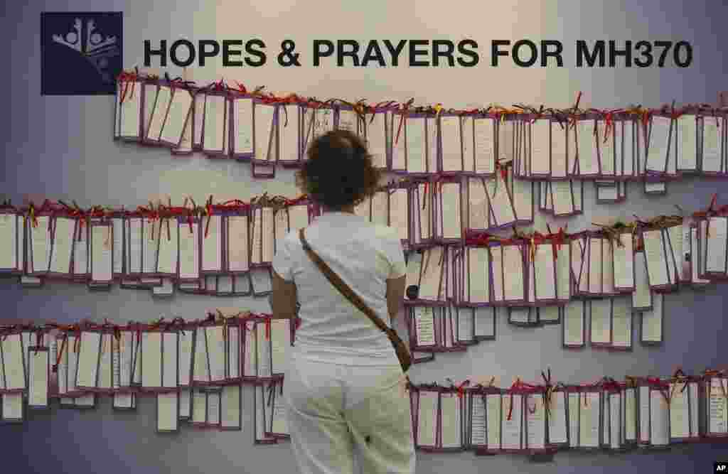 Seorang perempuan membaca kartu-kartu berisi pesan untuk para penumpang pesawat penerbangan MH370 di sebuah pusat perbelanjaan di Kuala Lumpur, 24 Maret 2014.