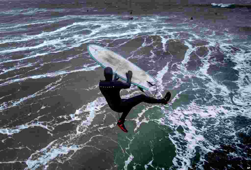 A surfer jumps into the storm-beaten Baltic Sea from the pier in Timmendorfer Strand, Germany, as temperatures reached 2° C.