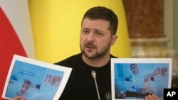 Президент Украины Владимир Зеленский демонстрирует фотографии находящегося в заключении экс-президента Грузии Михаила Саакашвили (архивное фото)