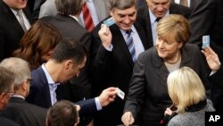 La canciller alemana Angela Merkel, a la derecha, vota este viernes en el parlamento de su país, en Berlin, Germany, Dec.4, 2015. 