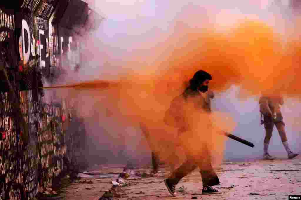 Riot police sprays powder on a demonstrator during a protest on International Women's Day, in Mexico City, Mexico, March 8, 2021.