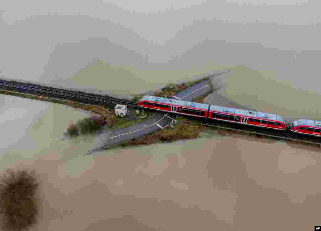 A train passes a rail road crossing that is surrounded by flooding caused by rain and melting snow in Nidderau near Frankfurt, Germany.