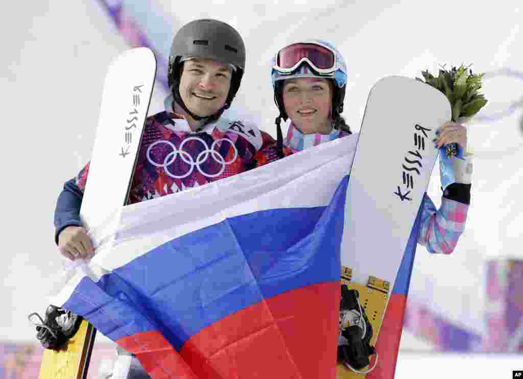 Russia's Vic Wild (left) poses after winning the gold medal in the men's snowboard parallel giant slalom final, with his wife and bronze medalist in the women's snowboard parallel giant slalom final, Russia's Alena Zavarzina, Krasnaya Polyana, Russia, Feb. 19, 2014.