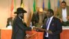 South Sudan's President Salva Kiir (front L) and South Sudan's rebel commander Riek Machar exchange documents after signing a cease-fire agreement during the Inter Governmental Authority on Development (IGAD) Summit on the case of South Sudan in Ethiopia'