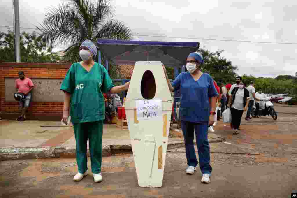 Nurses who work at the Hospital de Clinicas hold up an empty coffin with the Spanish message "Corruption kills" before the start of a protest demanding more medical supplies, outside their public hospital in San Lorenzo, Paraguay.