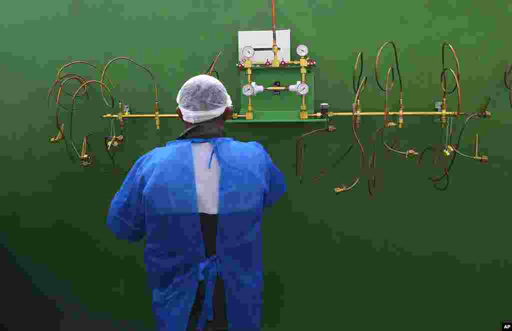 A health worker stands in front of an empty oxygen tank station, the only station at Joventina Dias Hospital, a small clinic in Manaus, Brazil.