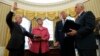 President Donald Trump watches as Vice President Mike Pence administers the oath of office to Attorney General Jeff Sessions, accompanied by his wife Mary, Feb. 9, 2017, in the Oval Office of the White House in Washington.