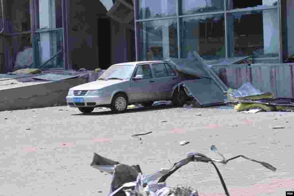天津爆炸事故現場,核心爆炸區週圍多座居民樓窗戶被震碎,高速公路橋樑受損,多輛大貨車被炸翻,小汽車起火或被砸,多名當地居民仍逗留在事故現場。(美國之音記者東方拍攝)