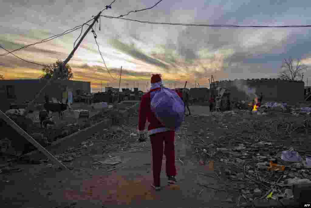 A man dressed as Santa Claus arrives to distribute toys to children living in an impoverished neighborhood in Iraq's southern city of Basra, Dec. 26, 2020.