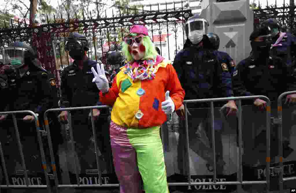 A pro-democracy protester wearing a clown costume raises a three-finger salute in front of riot police at Police Headquarter in Bangkok, Thailand. Protesters gathered to call for fairness for low-ranking police.