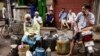 Ethnic Chinese Indians rest behind vendors selling their ware at a roadside market in Kolkata, India, Friday, June 19, 2020. India's prime minister is meeting top opposition leaders Friday as the government tries to lower tensions with China after…