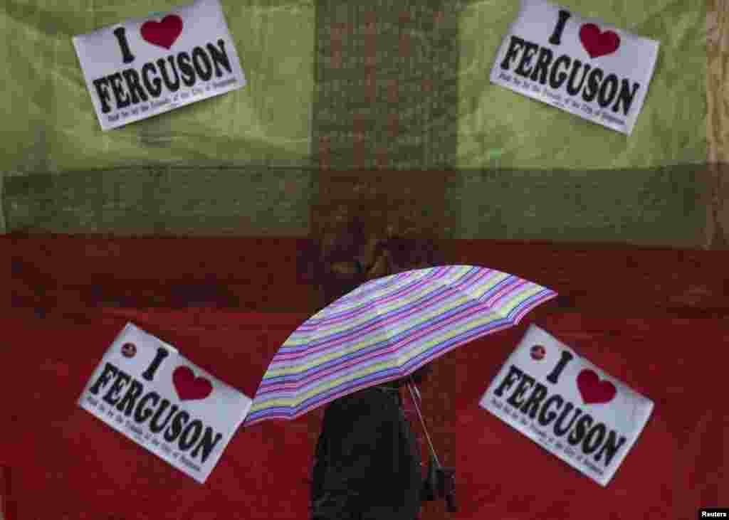 Cư dân đi ngang qua một cửa hàng bị bỏ hoang ở Ferguson với các khẩu hiệu ủng hộ Michael Brown.