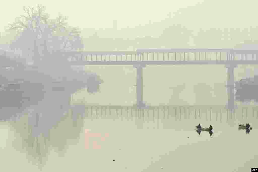 Boatmen row their boats in the waters of river Jhelum amid foggy condition in Srinagar, India.