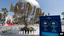 ARCHIVO - Entrada de Universal Studios Hollywood con un letrero de los protocolos COVID-19 implementados en Los Ángeles, el 16 de abril de 2021. 