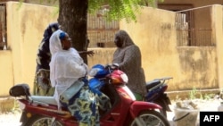 Women chat while sitting on their bikes in a district of Maroua, Cameroon, Nov. 20, 2013. 