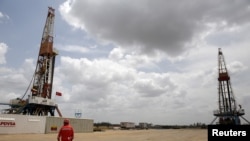 Un trabajador de un yacimiento petrolífero camina junto a plataformas de perforación en un pozo operado por la petrolera estatal venezolana, PDVSA., 16 de abril, 2015. REUTERS/Carlos Garcia Rawlins/File Photo