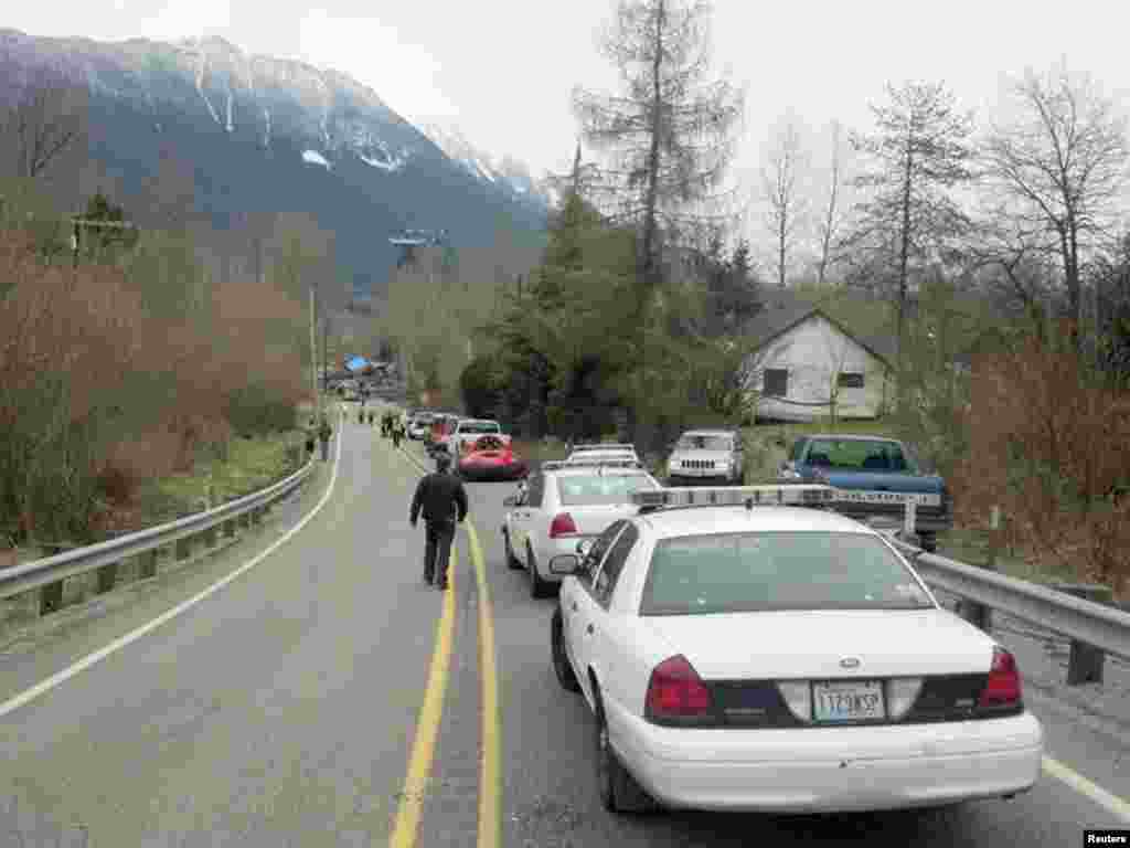 Para petugas dan mobil-mobil mengantre di jalan layang di lokasi tanah longsor dekat Oso, Washington (22/3).