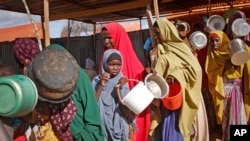 FILE - Women who fled drought queue to receive food distributed by local volunteers at a camp for displaced persons in the Daynile neighborhood on the outskirts of the capital Mogadishu, in Somalia, May 18, 2019.